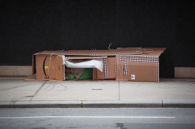 A man sleeps inside boxes on Madison Avenue.